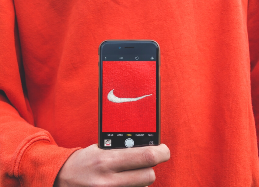 nike brand mark in red and white on phone screen held by a man